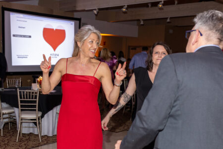Guests celebrating on the dance floor in front of a donation total screen at a Cleveland corporate gala with live donation counter displayed in background.